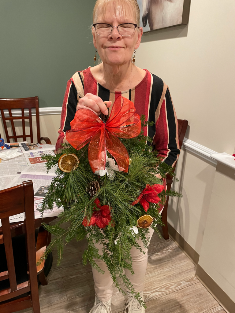 A resident is seen smiling, holding a wreath they made